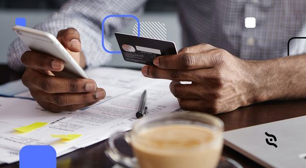 mão de gestor segurando um cartão e um celular utilizando solução de pagamento para empresas